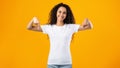 Happy Curly Woman Pointing Fingers Down Posing Over Yellow Background Royalty Free Stock Photo