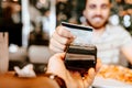 Happy customer paying for lunch using new, modern contactless technology with credit card