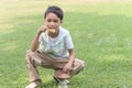 Happy cute Asian boy blowing soap bubbles while sitting on green grass in nature garden park. Kid spending time outdoors in meadow Royalty Free Stock Photo