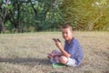 Happy cute Asian boy play game with smartphone sit on the park Royalty Free Stock Photo