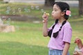 Happy cute Asian girl with pigtails blowing soap bubbles in green nature garden. Kid spending time outdoor in meadow. Cute child Royalty Free Stock Photo