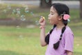 Happy cute Asian girl with pigtails blowing soap bubbles in green nature garden. Kid spending time outdoor in meadow. Cute child Royalty Free Stock Photo