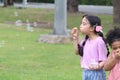 Happy cute Asian girl with pigtails blowing soap bubbles in green nature garden. Kid spending time outdoor in meadow. Cute child Royalty Free Stock Photo