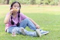 Happy cute Asian girl with pigtails blowing soap bubbles while sitting on green grass in nature garden park. Kid spending time Royalty Free Stock Photo