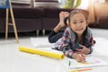 Happy cute asian little girl drawing using colorful pencils while lying on the floor Royalty Free Stock Photo