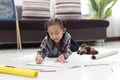 Happy cute asian little girl drawing using colorful pencils while lying on the floor Royalty Free Stock Photo