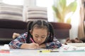 Happy cute asian little girl drawing using colorful pencils while lying on the floor Royalty Free Stock Photo