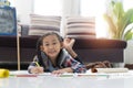 Happy cute asian little girl drawing using colorful pencils while lying on the floor Royalty Free Stock Photo