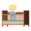 Happy cute baby boy in blue sleepwear body suit standing in the wooden crib with two mattress