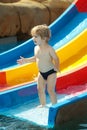 Happy cute baby boy rides from waterslide Royalty Free Stock Photo