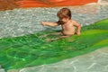 Happy cute baby boy slides from green waterslide Royalty Free Stock Photo