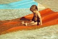 Happy cute baby boy slides from orange waterslide Royalty Free Stock Photo