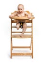 Happy cute baby girl sitting in high chair over white Royalty Free Stock Photo