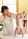 Happy cute baby at health exam at doctor`s office. Pediatrician supports infant kid while he is standing Royalty Free Stock Photo