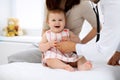 Happy cute baby with mother at health exam at doctor`s office. Medicine and health care concept Royalty Free Stock Photo