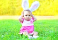 Happy cute baby with rabbit ears on grass in sunny spring Royalty Free Stock Photo