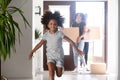 African parents entering new home with kid running in hallway Royalty Free Stock Photo