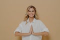 Happy cute blond girl in white shirt pressing palms together in pray or please gesture