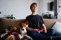 Happy cute boy playing video game console seated on a sofa with basenji dog puppy close in living room at home Royalty Free Stock Photo