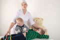 Happy cute boys playing with stethoscope in doctors office, hugging plush toy bear and smiling at camera. Female pediatrics Royalty Free Stock Photo