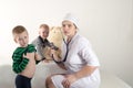 Happy cute boys playing with stethoscope in doctors office, hugging plush toy bear and smiling at camera. Female pediatrics. Copy Royalty Free Stock Photo