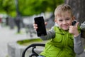 Happy child showing cell, smart phone, sitting on a city bench Royalty Free Stock Photo