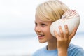 Happy cute child listening to sea in nautilus shell Royalty Free Stock Photo