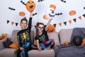 Happy cute children boy and girls in costume on sofa in living room during Halloween party.