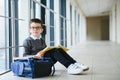 Happy cute clever boy in glasses with school bag and book in his hand. First time to school. Back to school. Royalty Free Stock Photo