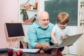 Happy cute clever boy and old tutor with book. Portrait of confident old male teacher. Learning and education concept