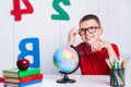 Happy cute clever boy is sitting at a desk in a glasses with rai Royalty Free Stock Photo