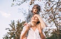 Happy cute daughter on a piggy back ride with her smiling mother on nature background. Loving woman and her little girl playing in Royalty Free Stock Photo
