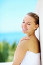 Happy cute female in towel leaning against a wall outside. Smiling young woman wrapped in a towel leaning against a wall Royalty Free Stock Photo