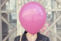 Happy cute girl hiding her face behind pink balloon Royalty Free Stock Photo