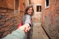 Happy cute girl leads guy in narrow street in Venice, Italy. Romantic travel to Venice. Lovers in Venezia. Surprise in travel. Royalty Free Stock Photo