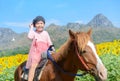 Happy cute girl riding horse in sunflower field Royalty Free Stock Photo