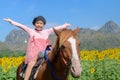 Happy cute girl riding horse in sunflower field Royalty Free Stock Photo