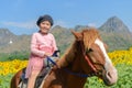 Happy cute girl riding horse in sunflower field Royalty Free Stock Photo