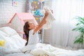 Happy cute girl sits on the bed in her children`s room and lifts Teddy bear up Royalty Free Stock Photo