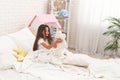 Happy cute girl sits on bed in her children`s room and plays with Teddy bear Royalty Free Stock Photo