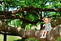 Happy cute girl sitting on branch huge tree