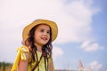 A happy cute girl, in a straw hat , stands in nature in the summer, against the background of a blue sky, looks away Royalty Free Stock Photo