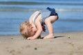 Happy cute girl in swimsuit playing with sand on beach Royalty Free Stock Photo