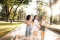 Happy cute girls of different races are chatting and walking in the park. Charming friends laugh and have fun together on the Royalty Free Stock Photo