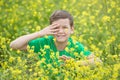 Happy cute handsome little kid boy on green grass lawn with blooming yellow dandelion flowers on sunny spring or summer day. Littl Royalty Free Stock Photo