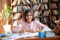 Happy cute hispanic indian school girl studying at table at home, portrait. Royalty Free Stock Photo