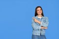 Happy Latin teenage student girl pointing aside isolated on blue background. Royalty Free Stock Photo