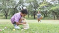 Happy cute little Asian child boy hunting Easter eggs. kid collecting eggs in basket, playing hunt eggs game with friends while