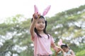 Happy cute little Asian child girl hunting Easter eggs, wearing bunny ears. kids holding basket, holding and showing eggs on hand Royalty Free Stock Photo