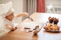 Happy cute little baby boy in a cook cap playing with flour at home kitchen Royalty Free Stock Photo